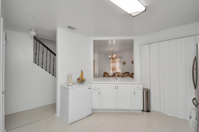 bar featuring hanging light fixtures, a textured ceiling, white cabinets, and an inviting chandelier