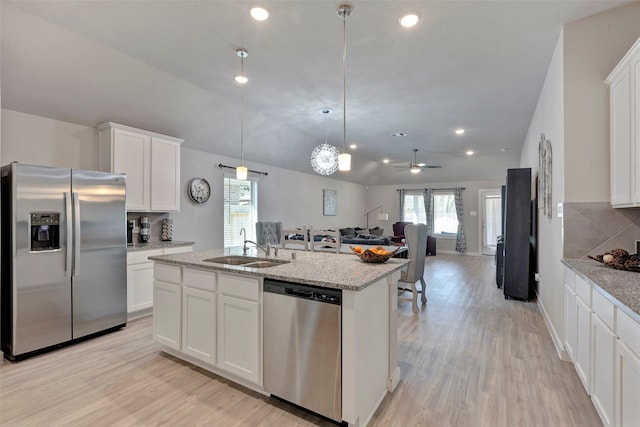 kitchen featuring sink, white cabinetry, hanging light fixtures, appliances with stainless steel finishes, and an island with sink