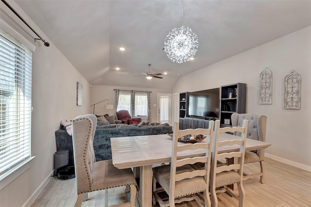 dining room with ceiling fan with notable chandelier, vaulted ceiling, and light hardwood / wood-style floors