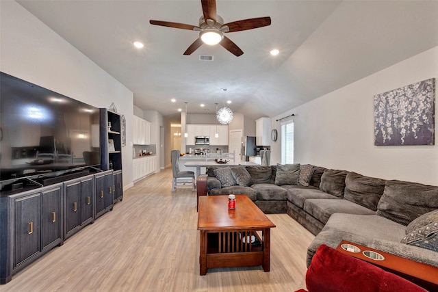 living room featuring vaulted ceiling, light hardwood / wood-style floors, and ceiling fan