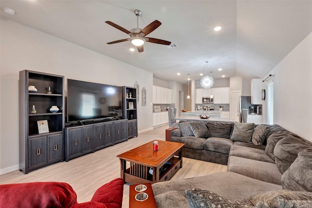 living room featuring vaulted ceiling, ceiling fan, and light wood-type flooring