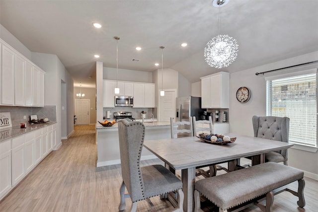 dining room with lofted ceiling, light hardwood / wood-style floors, and a notable chandelier