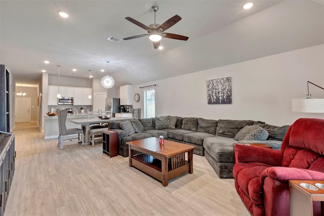 living room with vaulted ceiling, ceiling fan, and light wood-type flooring