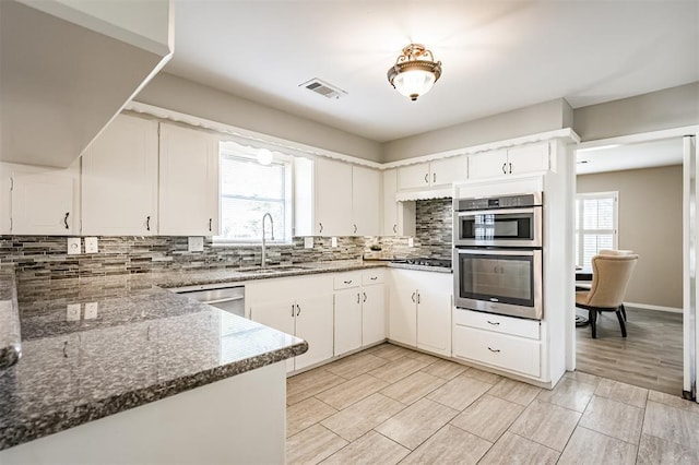 kitchen with sink, tasteful backsplash, appliances with stainless steel finishes, dark stone counters, and white cabinets