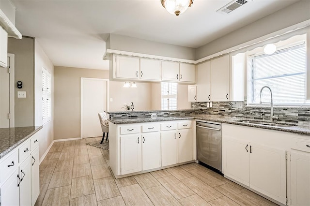 kitchen with white cabinetry, sink, stainless steel dishwasher, and kitchen peninsula