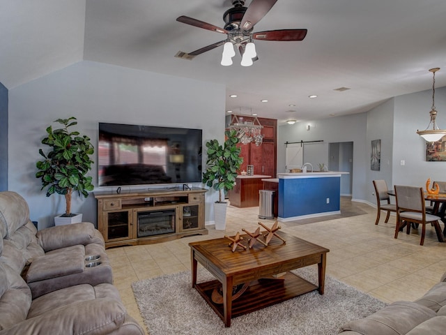 living room with a fireplace, a barn door, ceiling fan, and light tile patterned flooring