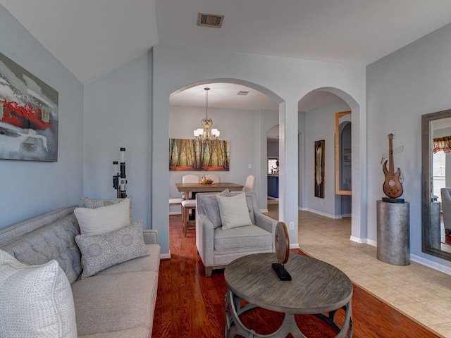 living room featuring hardwood / wood-style flooring, lofted ceiling, and a chandelier