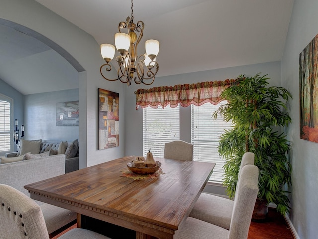 dining space with hardwood / wood-style flooring, lofted ceiling, a healthy amount of sunlight, and a chandelier