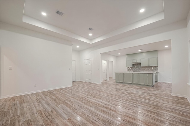 unfurnished living room with a raised ceiling and light hardwood / wood-style flooring