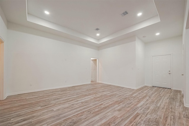 empty room with light hardwood / wood-style flooring and a tray ceiling