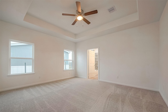 carpeted empty room with a raised ceiling and ceiling fan