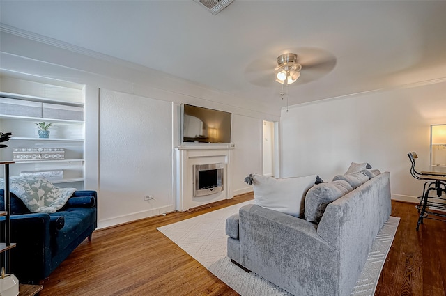 living room featuring hardwood / wood-style flooring, ornamental molding, and ceiling fan