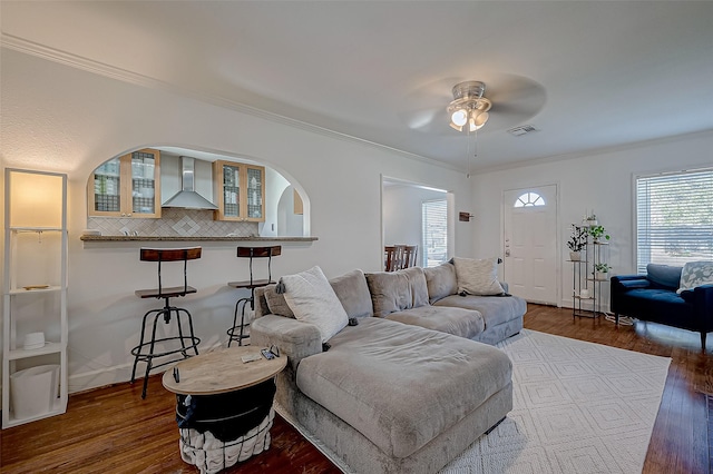 living room with crown molding, dark wood-type flooring, and ceiling fan