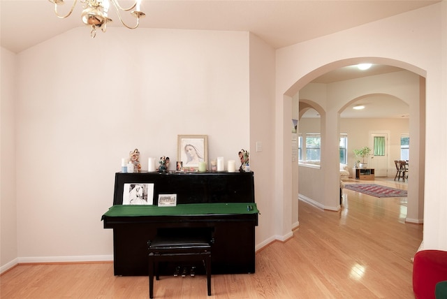 misc room with vaulted ceiling, hardwood / wood-style floors, and an inviting chandelier