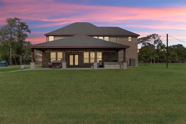 back house at dusk featuring a yard and a patio area