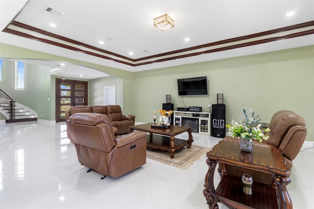 tiled living room with crown molding and a raised ceiling