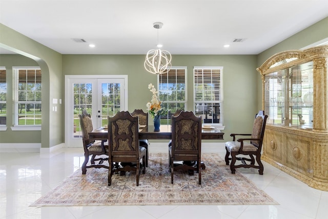 tiled dining space with a wealth of natural light, an inviting chandelier, and french doors