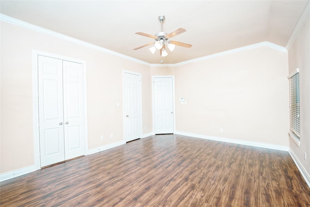 unfurnished bedroom with dark hardwood / wood-style flooring, ceiling fan, crown molding, and multiple closets