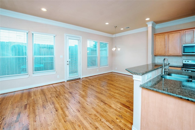 kitchen with sink, appliances with stainless steel finishes, dark stone countertops, kitchen peninsula, and light wood-type flooring