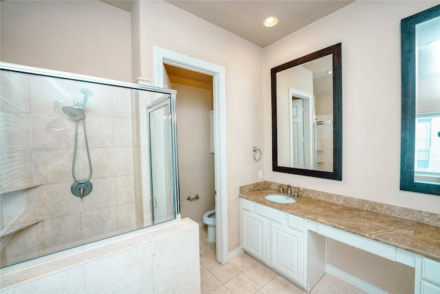 bathroom with a shower with door, vanity, tile patterned floors, and toilet