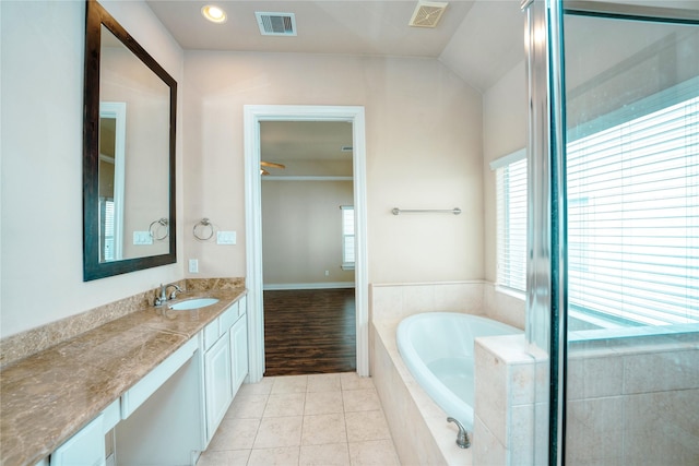 bathroom featuring vanity, a relaxing tiled tub, and tile patterned floors