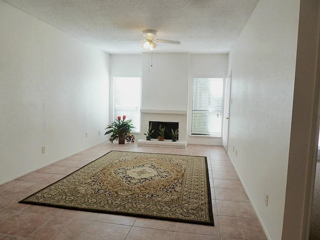 unfurnished living room featuring ceiling fan, a textured ceiling, and light tile patterned floors