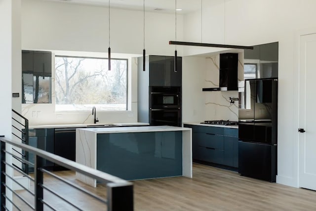 kitchen with modern cabinets, light wood-style flooring, black appliances, exhaust hood, and light countertops