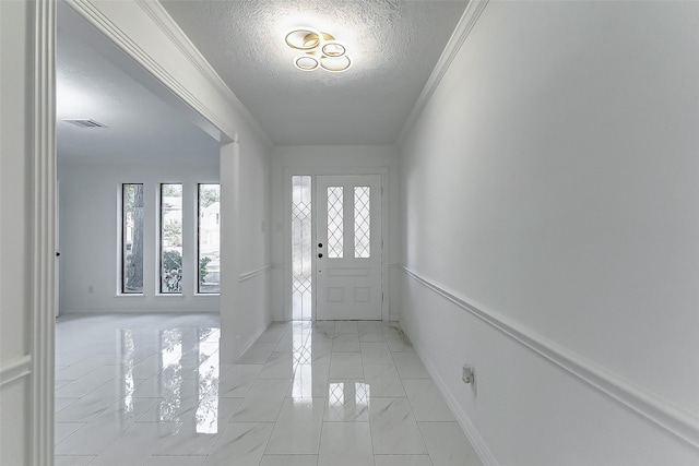 entryway with ornamental molding and a textured ceiling