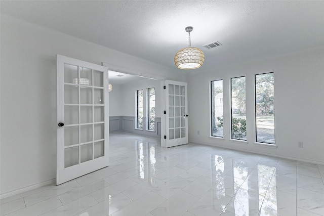 unfurnished room with french doors and a textured ceiling