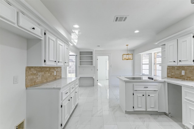 kitchen with light stone counters, a chandelier, hanging light fixtures, black electric cooktop, and white cabinets