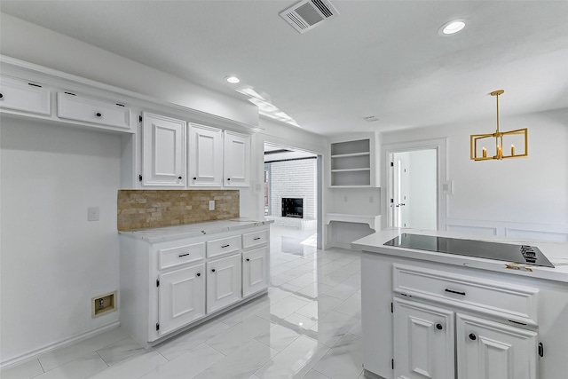 kitchen featuring pendant lighting, white cabinetry, decorative backsplash, black electric stovetop, and a brick fireplace