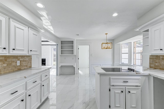 kitchen featuring decorative light fixtures, black electric stovetop, light stone countertops, decorative backsplash, and white cabinets