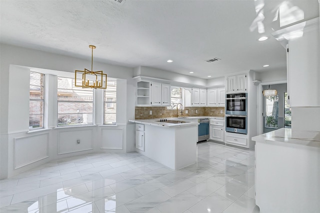 kitchen featuring white cabinetry, sink, backsplash, a chandelier, and hanging light fixtures