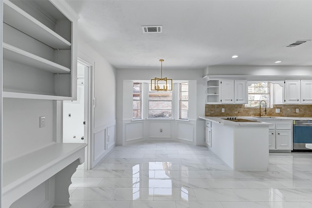 kitchen featuring sink, dishwasher, white cabinetry, hanging light fixtures, and tasteful backsplash