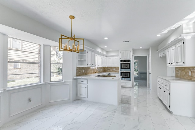 kitchen featuring pendant lighting, double oven, tasteful backsplash, sink, and white cabinets