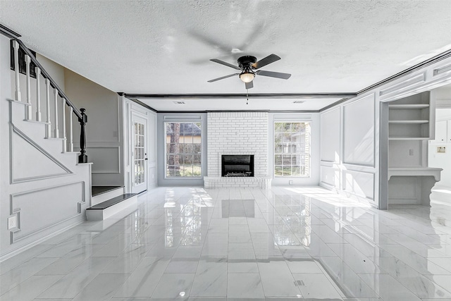 unfurnished living room with ceiling fan, a brick fireplace, and a textured ceiling