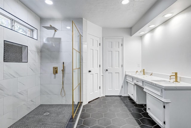 bathroom featuring vanity, tile patterned flooring, a textured ceiling, and a tile shower