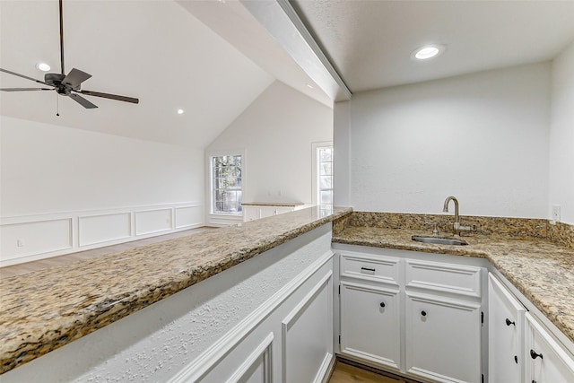 kitchen with sink, kitchen peninsula, and white cabinets