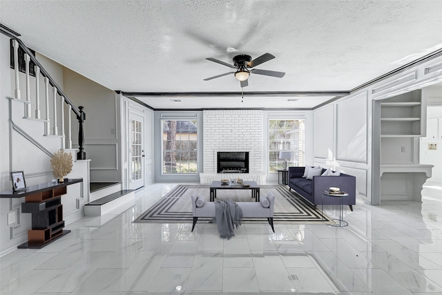 living room featuring ceiling fan, a brick fireplace, and a textured ceiling