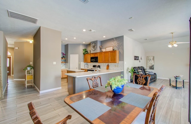 dining room with ceiling fan, lofted ceiling, and light hardwood / wood-style flooring