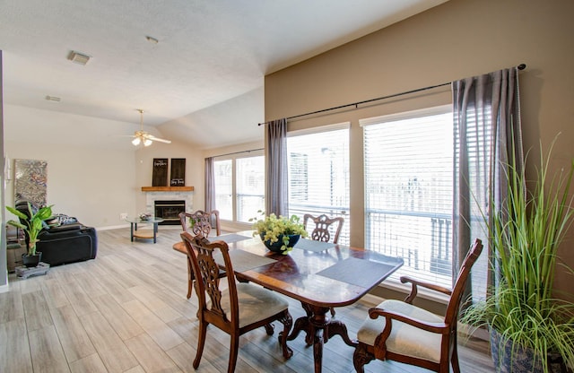 dining area with ceiling fan, lofted ceiling, plenty of natural light, and light hardwood / wood-style floors