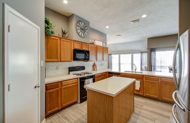 kitchen with sink, a center island, a textured ceiling, stainless steel appliances, and backsplash