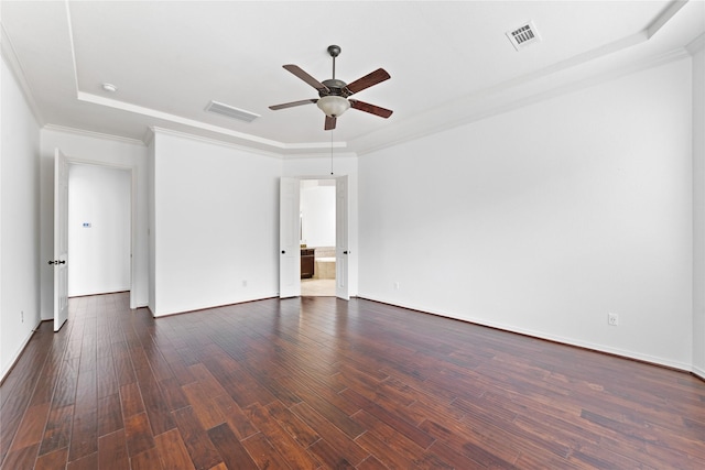 empty room featuring a tray ceiling, dark wood-type flooring, ornamental molding, and ceiling fan