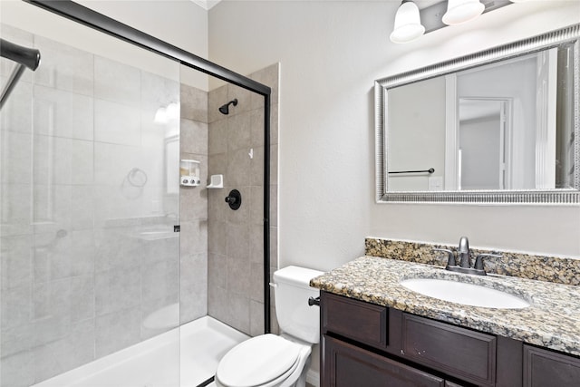 bathroom with vanity, toilet, and a shower with door