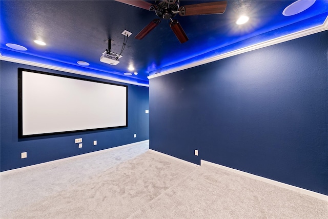 carpeted cinema with ceiling fan and a raised ceiling