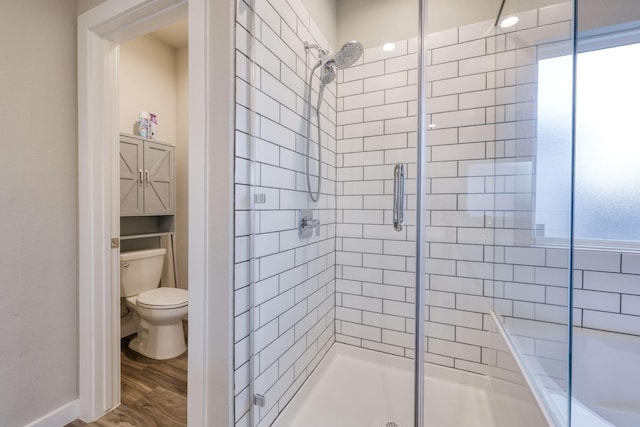 bathroom featuring toilet, a shower stall, and wood finished floors