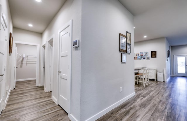 corridor with baseboards, recessed lighting, and light wood-style floors