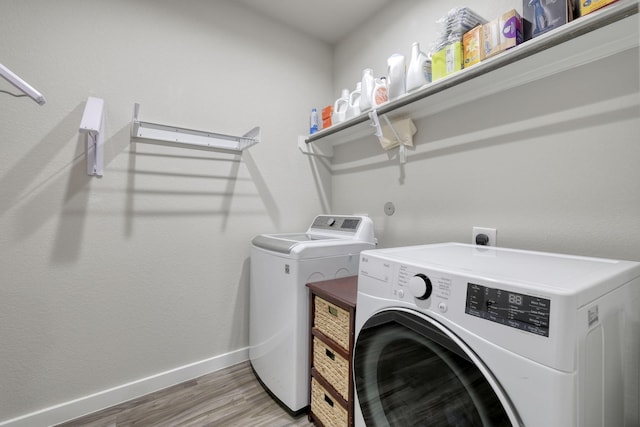 laundry room with laundry area, independent washer and dryer, baseboards, and wood finished floors