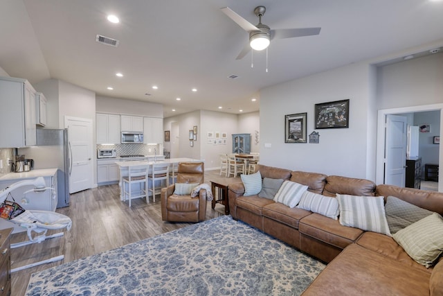 living room with a ceiling fan, wood finished floors, visible vents, and recessed lighting