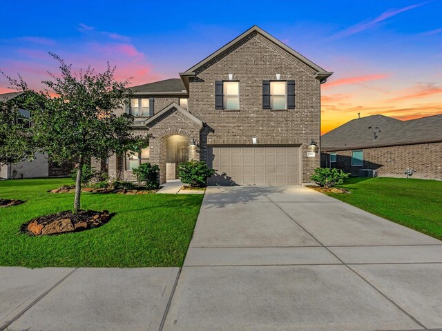 view of front of house featuring a garage, a yard, and central AC